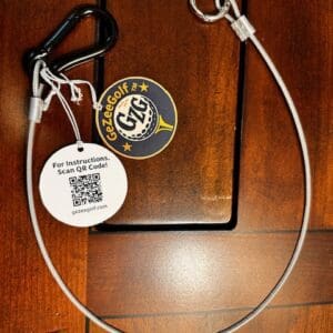 A dog leash with a carabiner and tags on a wooden surface.