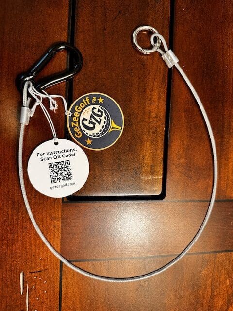 A dog leash with a carabiner and tags on a wooden surface.